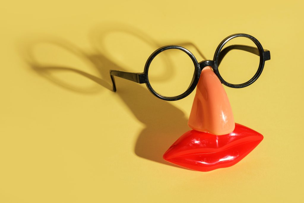 Header Image: funny fake face disguise: black glasses, nose, and mouth on bright yellow background (Credit: nito / Shutterstock.com)