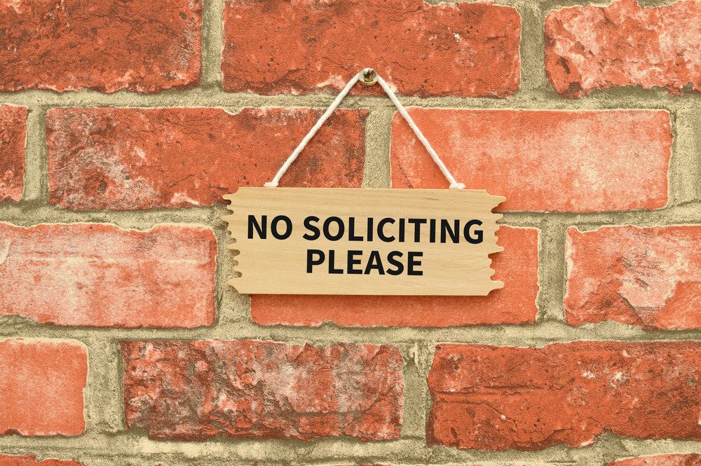 Header image: "No Soliciting Please" sign hanging on a red-brick wall (Credit: rSnapshotPhotos / Shutterstock.com)