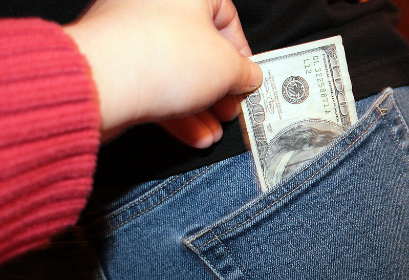 Header image: a hand surreptitiously slipping a $100 bill out of someone's back pocket (Credit: Kate Sumbler / Flickr.com)